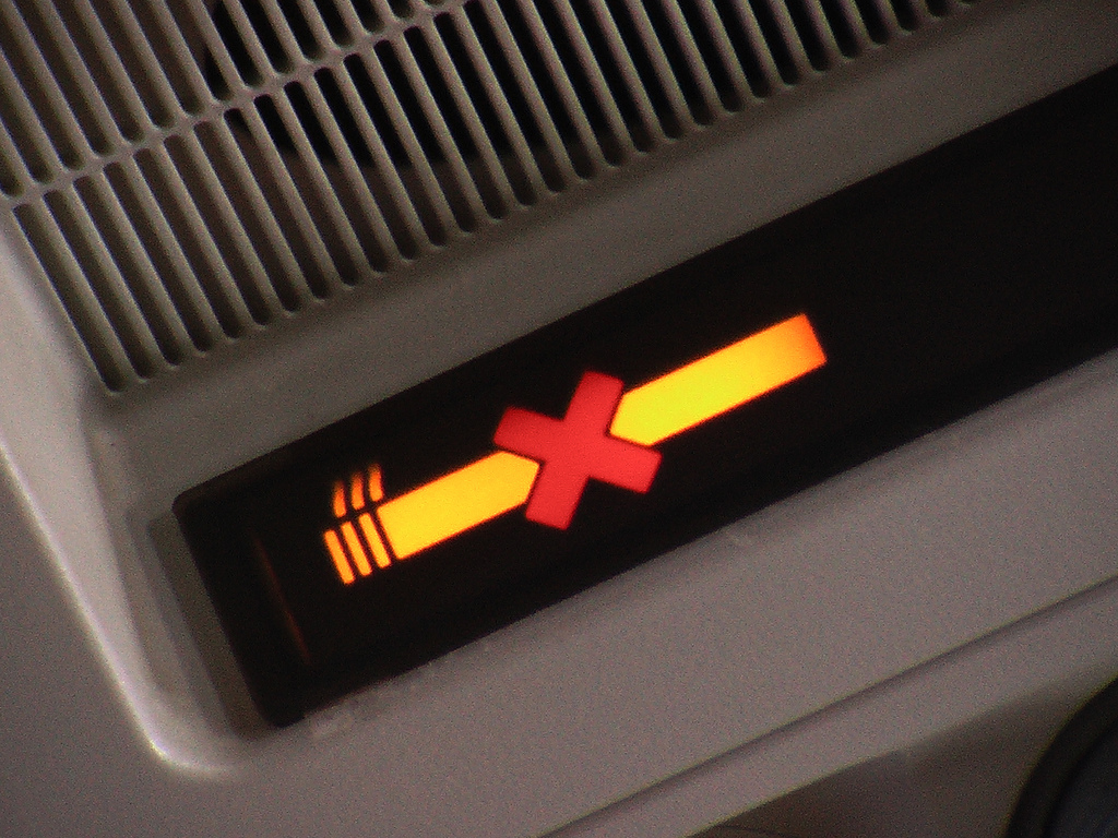 A lit no smoking sign above an airplane seat