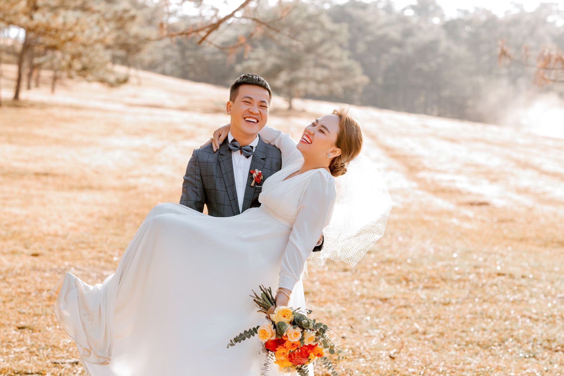 A groom carrying his bride outdoors